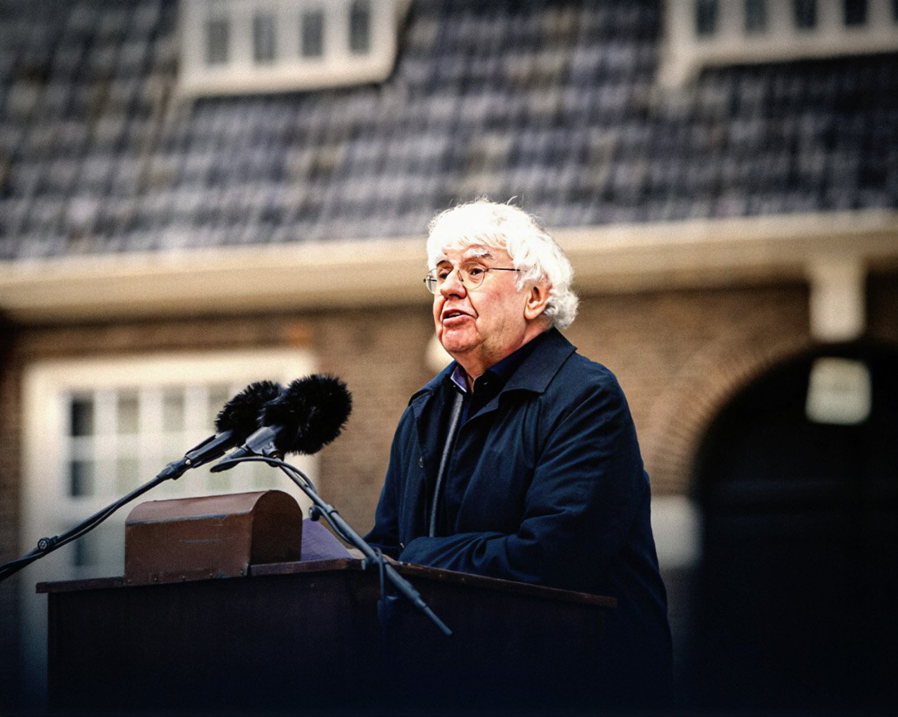 Geert Mak houdt een toespraak tijdens een evenement, sprekend over maatschappelijke en politieke kwesties.