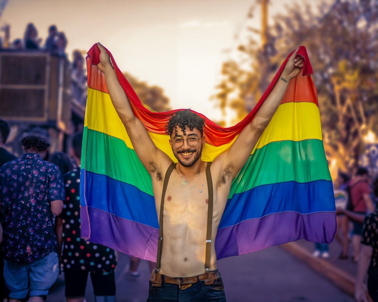 Man met LHBTIQA+-vlag die vrolijk lacht tijdens een Pride-evenement.