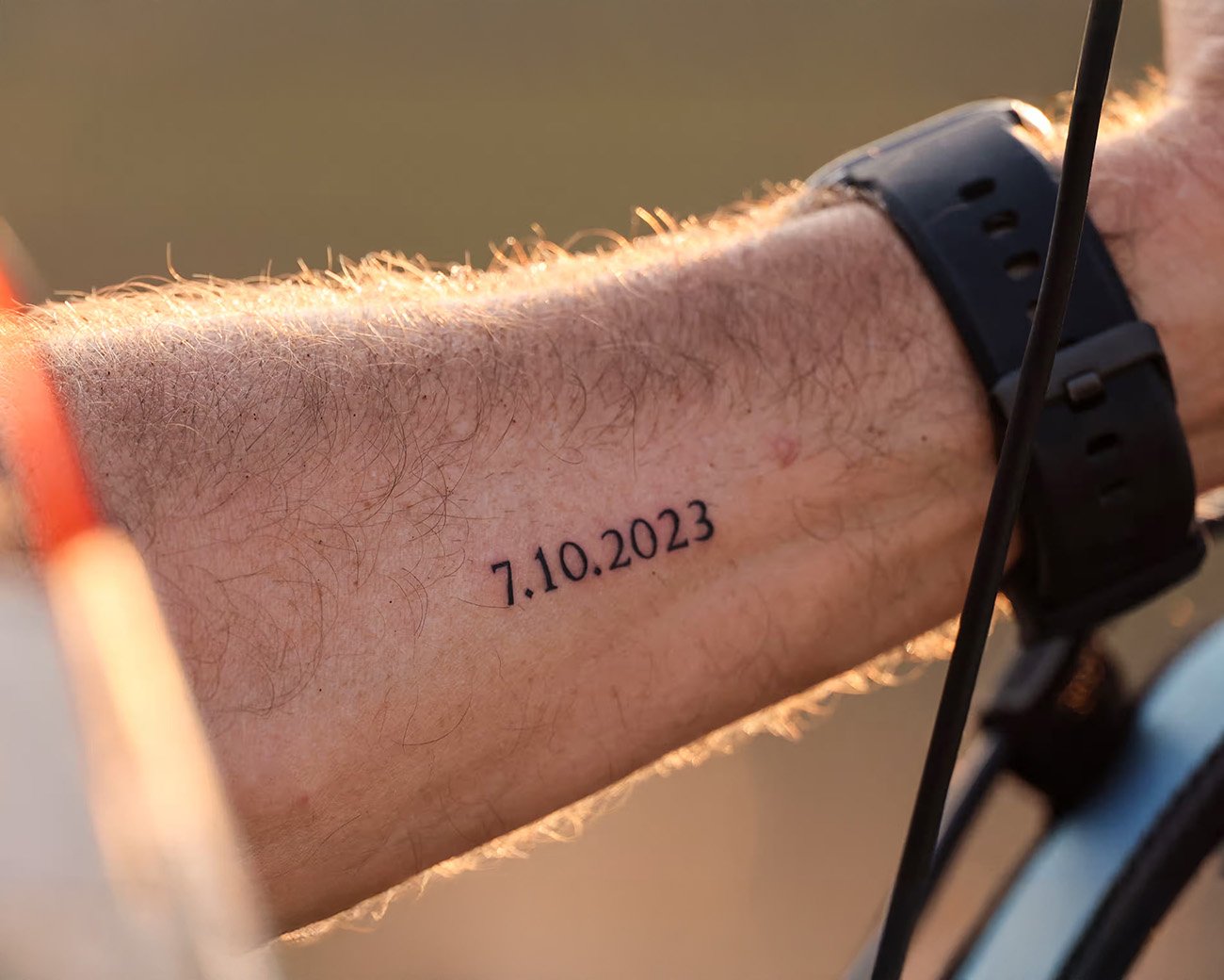 Close-up van een tatoeage met de datum 7.10.2023 op een onderarm.