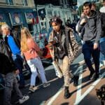 Straat in Amsterdam met drukte van toeristen en bewoners, symbool voor massatoerisme en overlast.