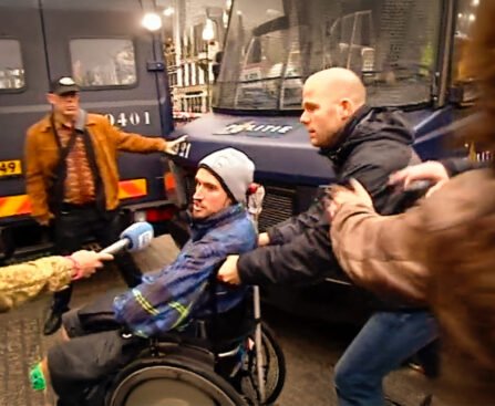 Demonstrant in rolstoel wordt door politieagent weggeduwd tijdens protest bij het Maagdenhuis.