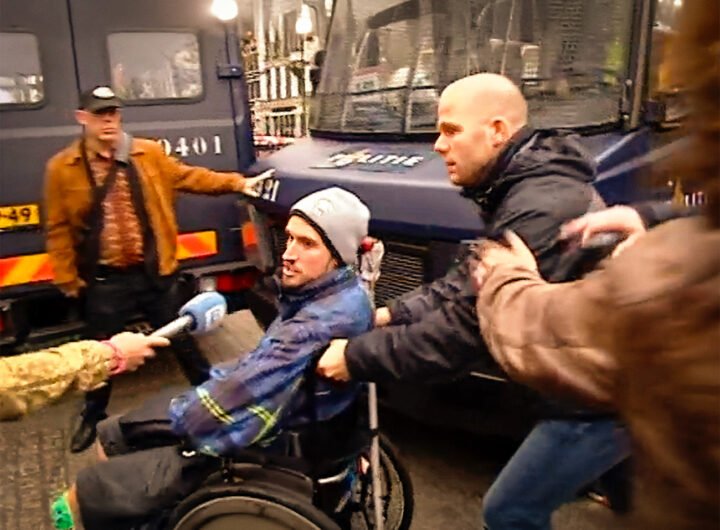 Demonstrant in rolstoel wordt door politieagent weggeduwd tijdens protest bij het Maagdenhuis.