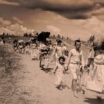 Palestijnse vluchtelingen lopen over een stoffige weg tijdens de Nakba in 1948, met bezittingen op hun rug en kinderen aan de hand.