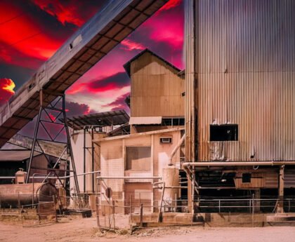 Afbeelding van een vervallen industriële fabriek met een dramatische rood getinte lucht, symboliserend de destructieve impact van economische groei en de noodzaak van degrowth.