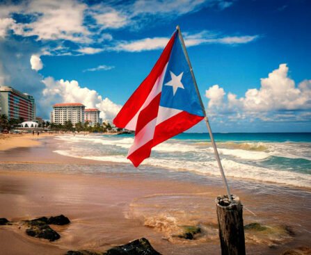 De vlag van Puerto Rico wappert op een strand met hotels en de oceaan op de achtergrond.