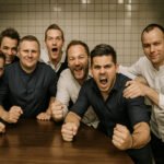 Team van jonge mannen toont enthousiasme en vastberadenheid in een werkruimte.