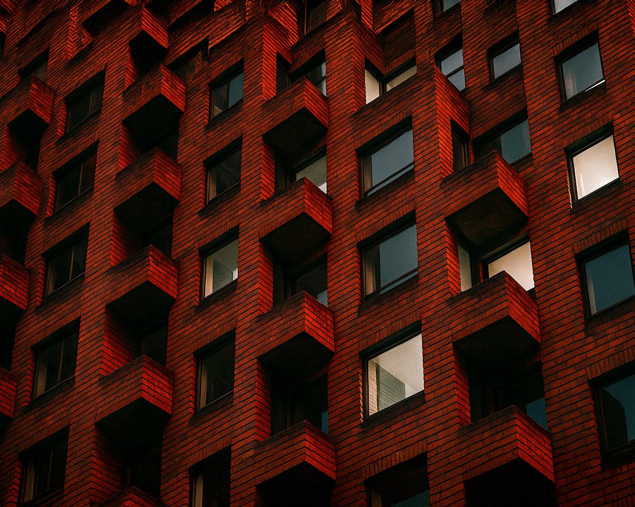 Gevel van een brutalistisch woongebouw met bakstenen en betonnen balkons, symbool van sociale woningbouw