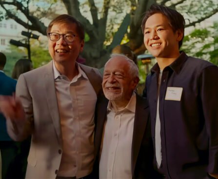 Robert Reich poseert met twee aanwezigen tijdens een bijeenkomst in de buitenlucht