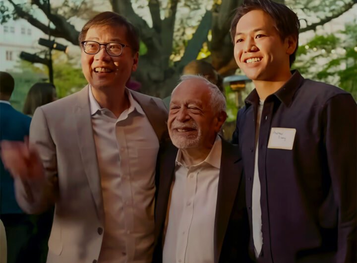Robert Reich poseert met twee aanwezigen tijdens een bijeenkomst in de buitenlucht