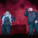Kneecap op het podium tijdens Glastonbury 2025 met Palestijnse sjaal en microfoon
