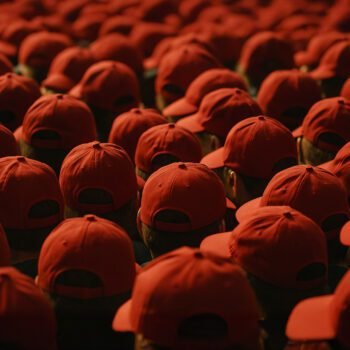 Grote groep mensen met identieke rode petjes, gezien van achteren