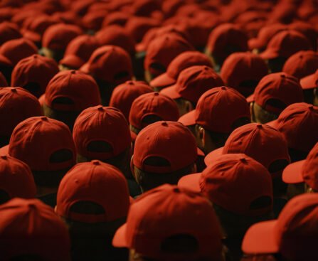 Grote groep mensen met identieke rode petjes, gezien van achteren