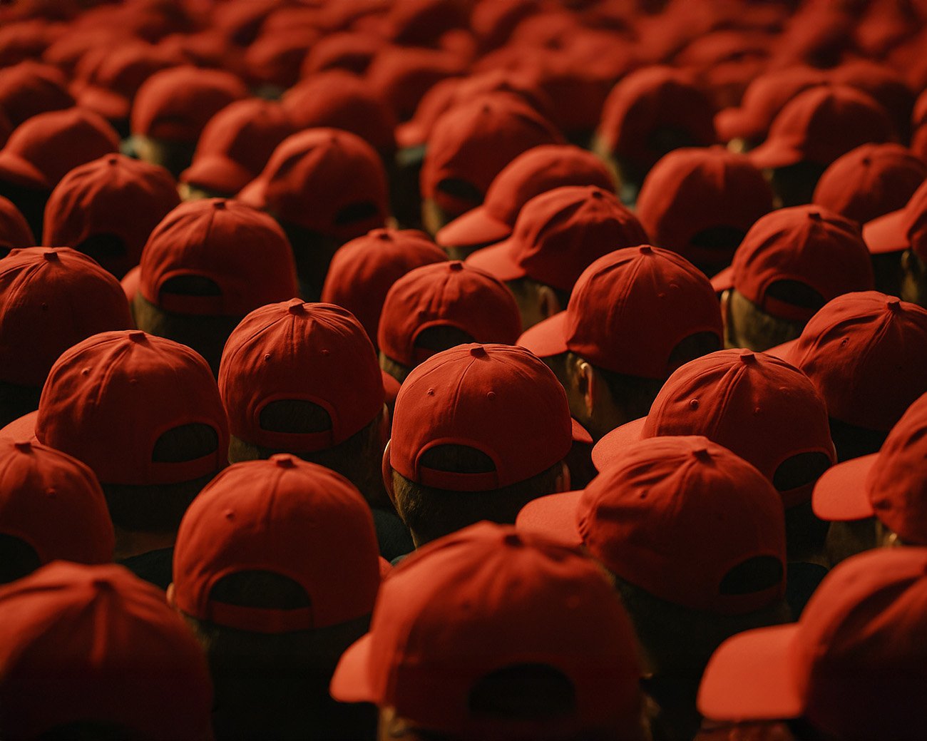 Grote groep mensen met identieke rode petjes, gezien van achteren