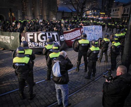 Politieagenten in gele hesjes houden een groep demonstranten met spandoeken tegen tijdens een protest tegen repressie en politiegeweld.