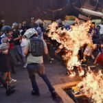 Demonstranten tijdens de guarimbas in Caracas, met een man die in brand staat.