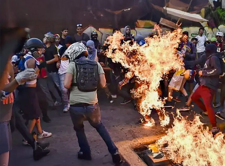 Demonstranten tijdens de guarimbas in Caracas, met een man die in brand staat.