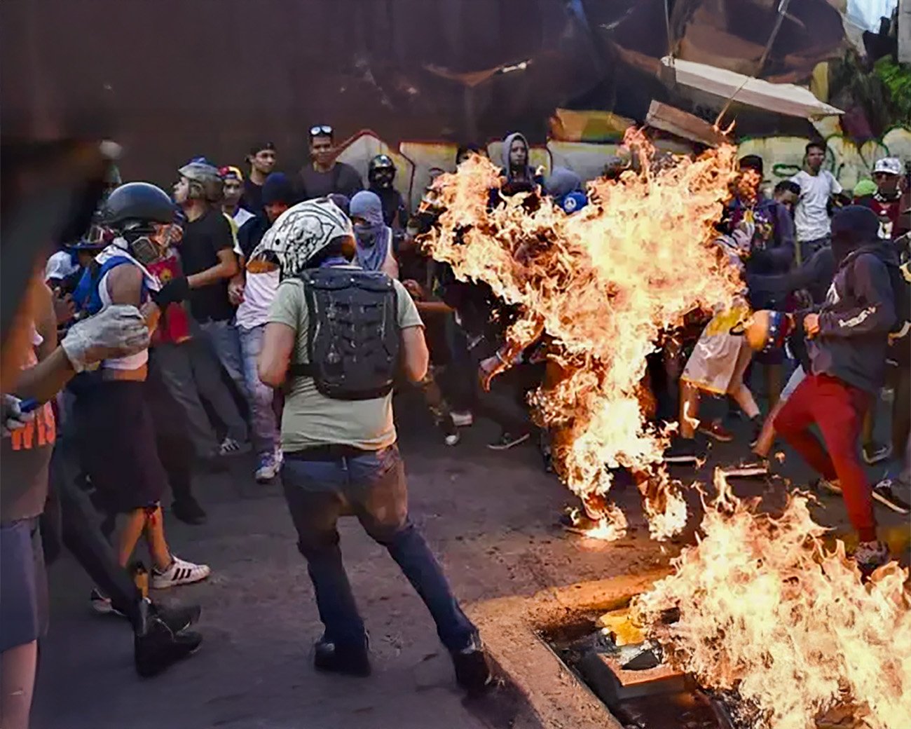 Demonstranten tijdens de guarimbas in Caracas, met een man die in brand staat.