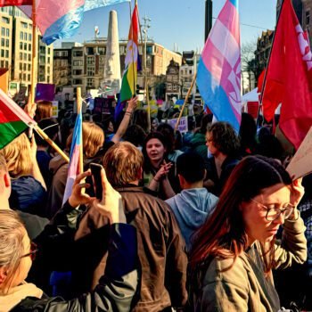 Een groep demonstranten op de Dam met vlaggen en protestborden tijdens een mars voor vrijheid en solidariteit in Amsterdam.