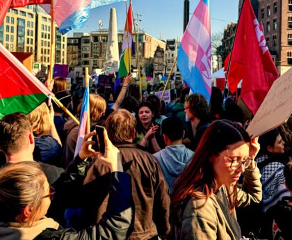Een groep demonstranten op de Dam met vlaggen en protestborden tijdens een mars voor vrijheid en solidariteit in Amsterdam.
