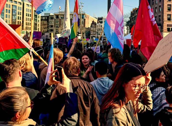 Een groep demonstranten op de Dam met vlaggen en protestborden tijdens een mars voor vrijheid en solidariteit in Amsterdam.