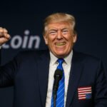 Donald Trump met gouden tanden en opgeheven vuist, lachend op een crypto-evenement