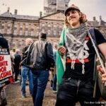 Demonstranten op de Dam met antiracisme-borden en een persoon die een Palestijnse sjaal draagt, tijdens een protest tegen haat en uitsluiting.
