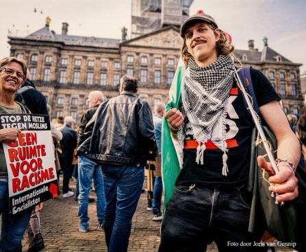Demonstranten op de Dam met antiracisme-borden en een persoon die een Palestijnse sjaal draagt, tijdens een protest tegen haat en uitsluiting.