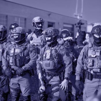Groep zwaarbewapende federale agenten staat opgesteld tijdens een grootschalige operatie in een stedelijke omgeving.