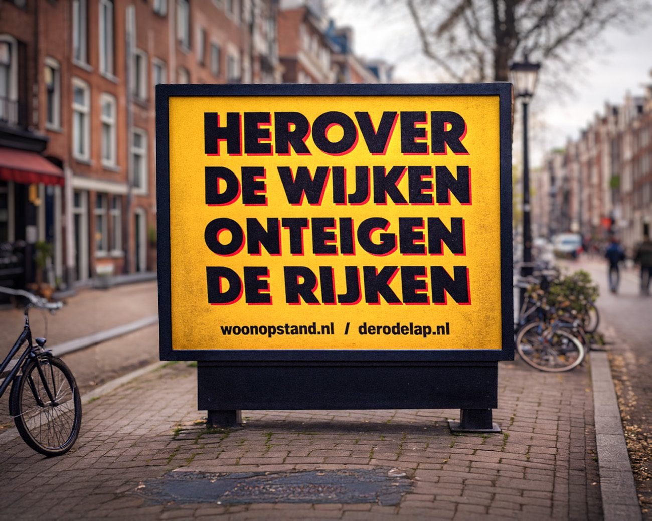 Gele actiebord met de tekst “Herover de wijken, onteigen de rijken” in een Amsterdams straatbeeld.