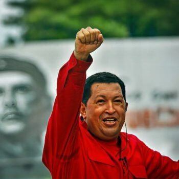 Hugo Chávez heft zijn vuist in de lucht, met een afbeelding van Che Guevara op de achtergrond
