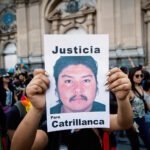 Een demonstrant houdt een bord omhoog met een geprinte portretfoto van een man en de woorden “Justicia” en “Para Catrillanca”, omringd door andere betogers.