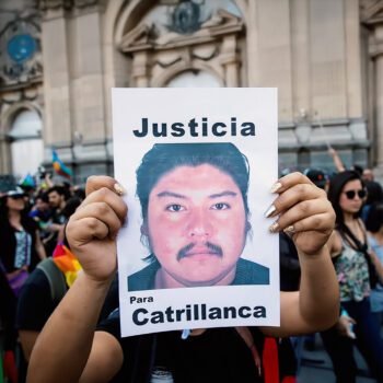 Een demonstrant houdt een bord omhoog met een geprinte portretfoto van een man en de woorden “Justicia” en “Para Catrillanca”, omringd door andere betogers.