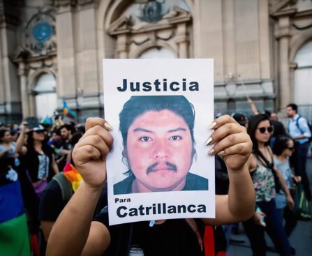 Een demonstrant houdt een bord omhoog met een geprinte portretfoto van een man en de woorden “Justicia” en “Para Catrillanca”, omringd door andere betogers.