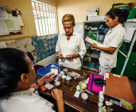 Drie zorgmedewerkers in een Venezolaanse kliniek sorteren medicijnen aan een tafel vol schaarse voorraden.