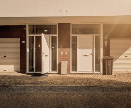 Straatportiek met meerdere deuren in Amsterdam, symboliserend lange wachttijden voor sociale huurwoningen en de strijd om woonzekerheid.
