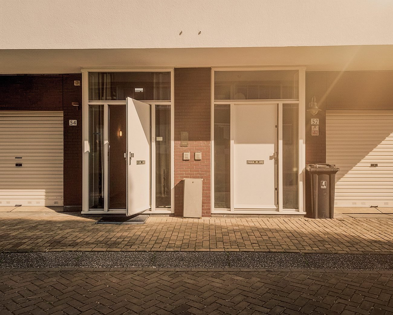 Straatportiek met meerdere deuren in Amsterdam, symboliserend lange wachttijden voor sociale huurwoningen en de strijd om woonzekerheid.