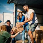 Vrijwilligers laden dozen met benodigdheden uit een vrachtwagen om ze te verdelen onder buurtgenoten die steun nodig hebben.