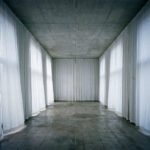 Lege institutionele ruimte met betonnen plafond en witte doeken die een tijdelijke morele façade suggereren