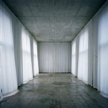 Lege institutionele ruimte met betonnen plafond en witte doeken die een tijdelijke morele façade suggereren