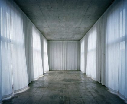 Lege institutionele ruimte met betonnen plafond en witte doeken die een tijdelijke morele façade suggereren