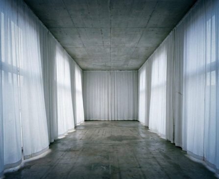 Lege institutionele ruimte met betonnen plafond en witte doeken die een tijdelijke morele façade suggereren