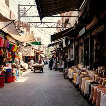Marktstraat in Qamişlo met zakken granen, winkels en mensen die zich door de straat bewegen