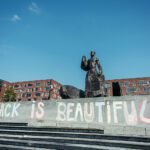 Standbeeld van Anton de Kom op het Anton de Komplein met op de trappen de graffiti Black is Beautiful