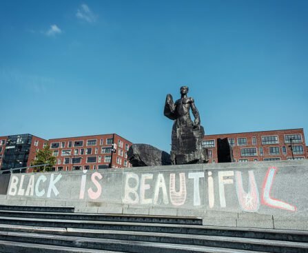 Standbeeld van Anton de Kom op het Anton de Komplein met op de trappen de graffiti Black is Beautiful