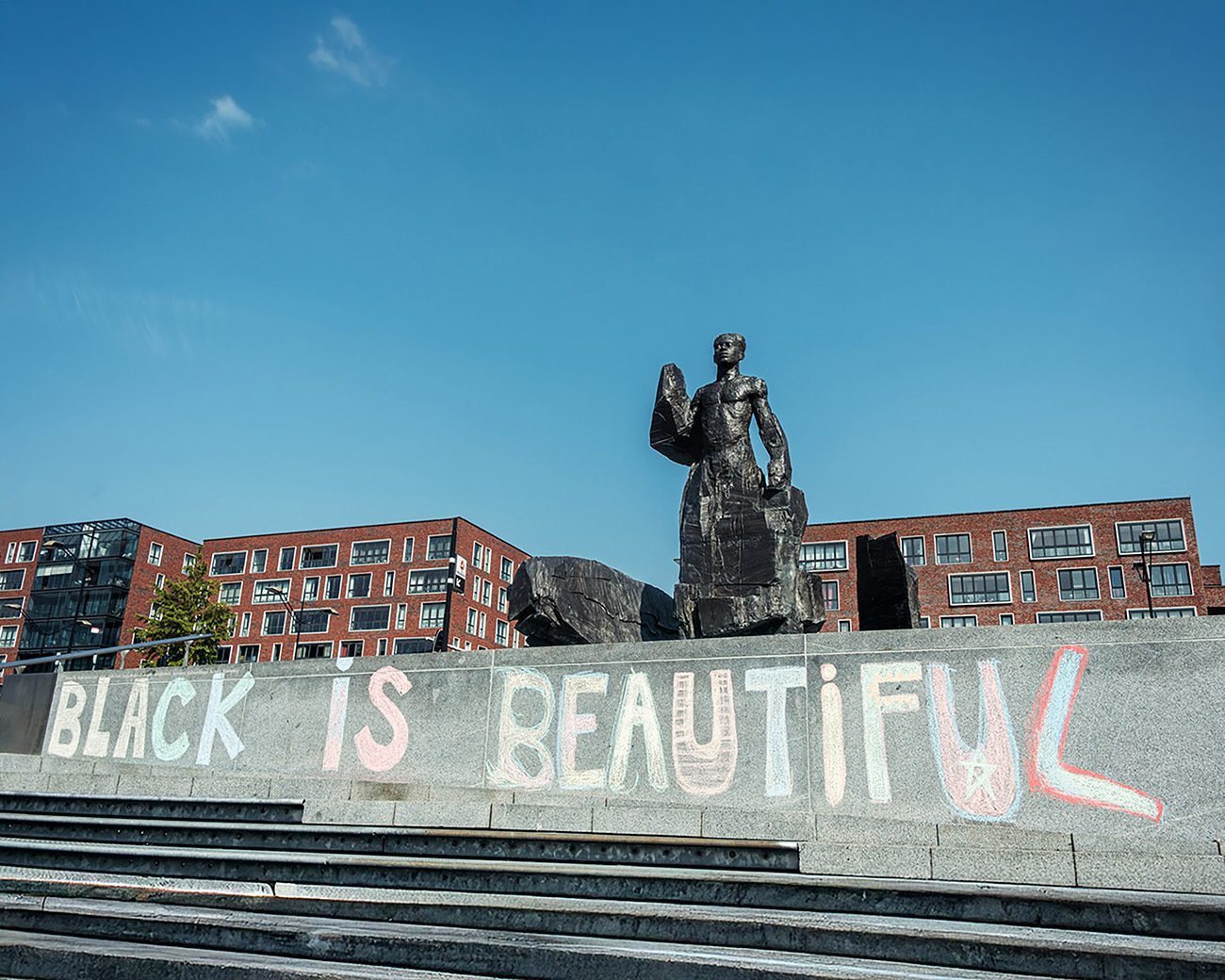 Standbeeld van Anton de Kom op het Anton de Komplein met op de trappen de graffiti Black is Beautiful