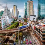 Skytrain boven een drukke straat in Bangkok met wolkenkrabbers op de achtergrond
