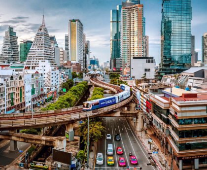Skytrain boven een drukke straat in Bangkok met wolkenkrabbers op de achtergrond