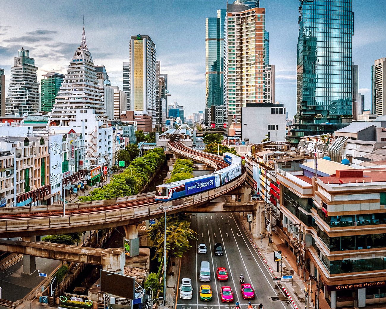 Skytrain boven een drukke straat in Bangkok met wolkenkrabbers op de achtergrond