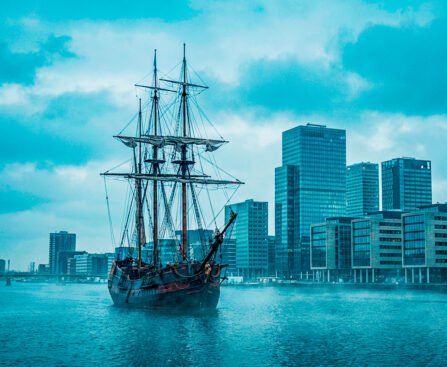 Historisch VOC-schip op het IJ met moderne kantoortorens van Amsterdam op de achtergrond