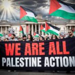 Demonstranten in Londen houden een spandoek met “We Are All Palestine Action” voor de National Gallery, met Palestijnse vlaggen en borden over het recht op protest.
